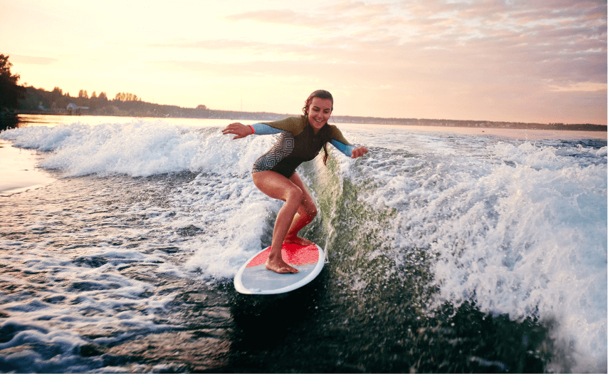 Woman surfing ocean waves at sunrise during summer