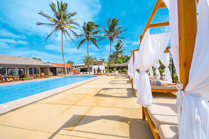 Resort poolside with cabanas and palm trees on a sunny day