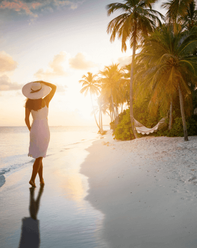 Woman walking on a tropical beach at Maldives sunset