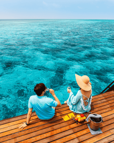 Couple relaxing with drinks by the turquoise Maldives sea