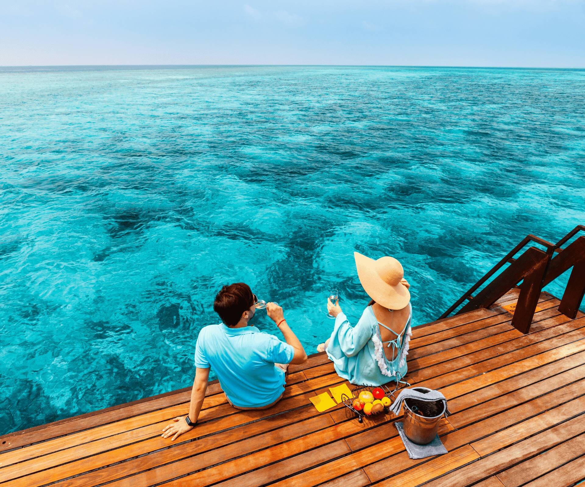 Couple relaxing with drinks by the turquoise Maldives sea