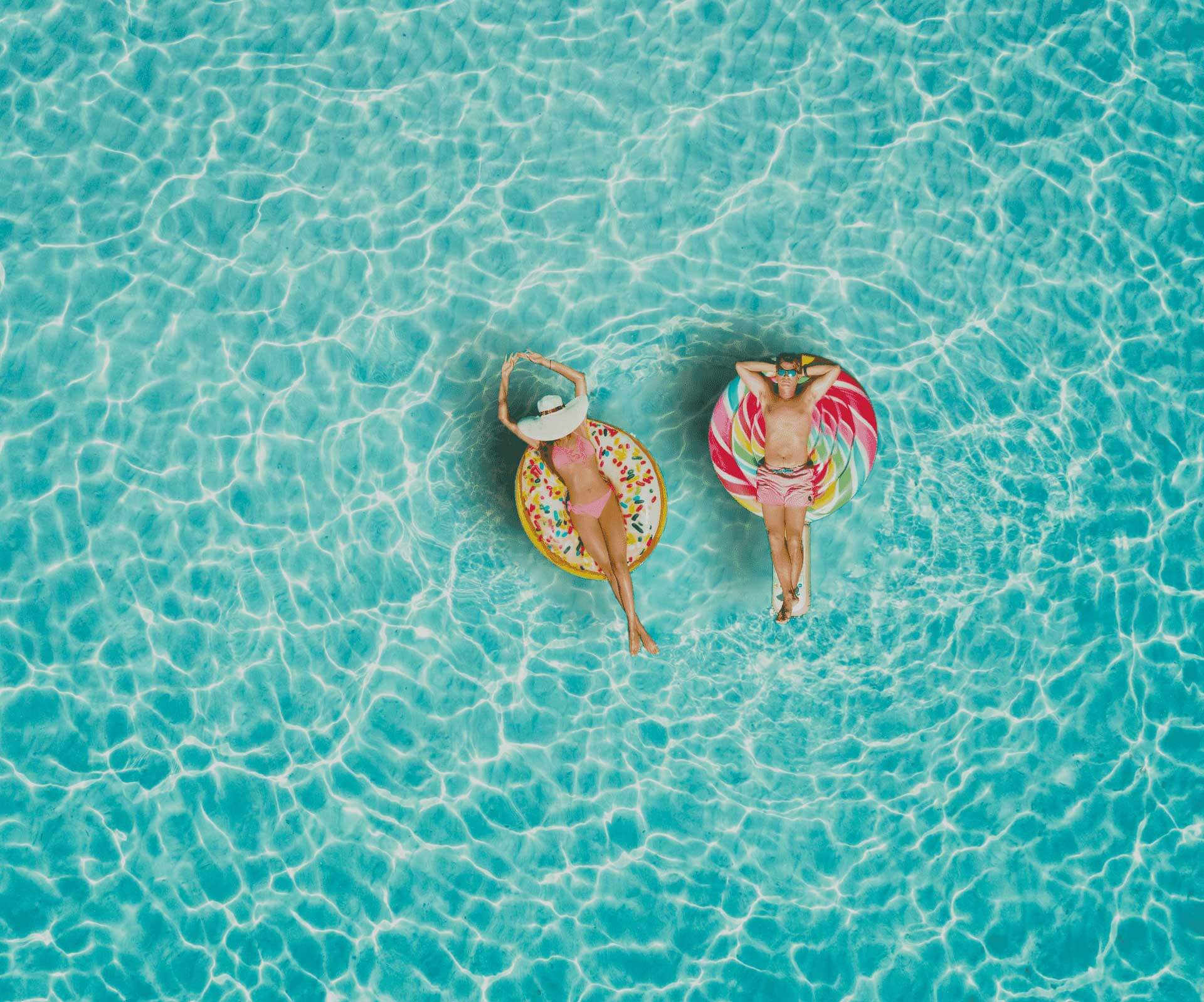 Couple relaxing on colorful floats in clear blue water